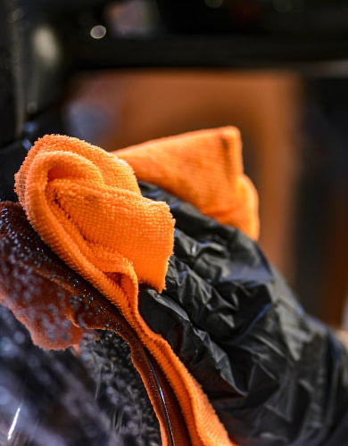 hand washing a car with an orange cloth